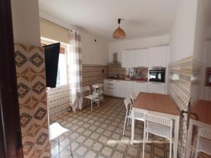 a kitchen with white cabinets and a table and chairs at Case Vacanze Tropea La Pinnata in Tropea