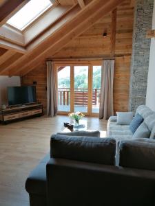 a living room with a couch and a television at Chalet les Ecureuils Apartment Penthouse Suite in Crésuz