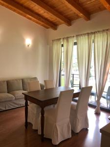 une salle à manger avec une table en bois et des chaises blanches dans l'établissement Residence i Fiori, à Piantedo