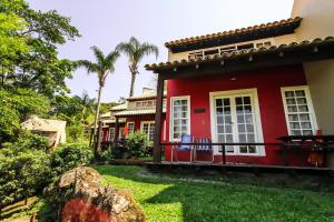 una casa roja con dos sillas en el patio en Pousada dos Ingleses en Bombinhas