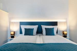 a bed with blue and white pillows and two lamps at Hotel Historischer Krug in Oeversee +27 photos
