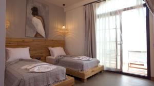 a bedroom with two beds and a large window at Dmira Alacati in Alaçatı