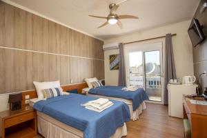 a hotel room with two beds and a window at Rea Hotel in Faliraki