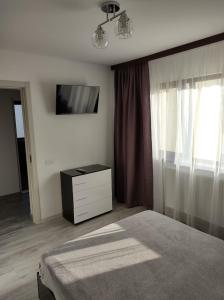 a bedroom with a bed and a dresser and a television at Casa Jolie in Constanţa