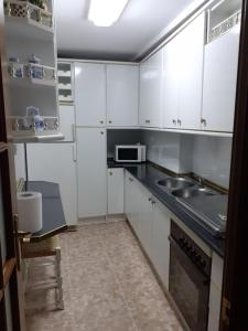 una cocina con armarios blancos y fregadero en Casa Manuel, en Úbeda