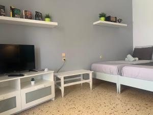 a room with two beds and a tv and a table at Villa Loula Apartment II in Poros