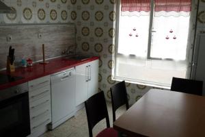 a kitchen with a sink and a table and a window at Apartamentos Campomanes 2 in Campomanes