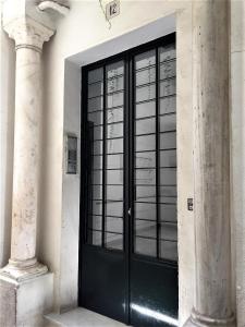 una puerta negra en un edificio con dos columnas en Luminoso y amplio apartamento en el centro histórico de Sevilla, en Sevilla