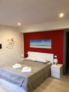 a bedroom with a large bed with a red wall at mammaCristina in Patti