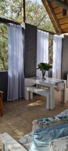 a patio with a table and a bench and white curtains at Forget me not Selfcatering Apartments in Nelspruit