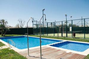 ein leerer Pool mit Tennisplatz im Hintergrund in der Unterkunft Apartamento diseño a cien metros del mar. in Torredembarra