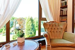 a living room with a chair and a table and a window at Medžiotojų Sostinė in Kunioniai