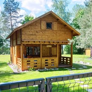 a log cabin in a field with a fence at Domek pod Sosnami z posesją na wyłączność Mazury Prażmowo in Prażmowo