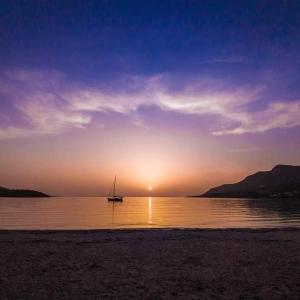 ein Segelboot im Wasser bei Sonnenuntergang in der Unterkunft AMMOESSA APARTMENTS in Plataria