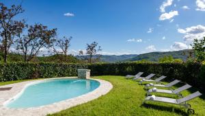 a row of lounge chairs next to a swimming pool at Villa Agostini 10, Emma Villas in Casa Nuova