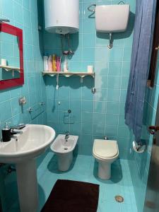 La salle de bains est pourvue de carrelage bleu, d'un lavabo et de toilettes. dans l'établissement Domus de Murta, à Pula