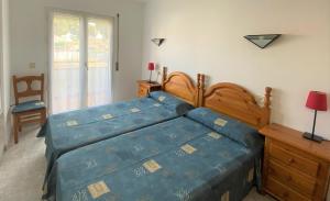 a bedroom with a bed with a blue comforter at Apartaments Club Nautic L'Escala in L'Escala