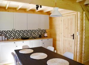 a kitchen with a black table and white cabinets at Klimatyzowany Domek z Sauną w lesie z posesją na wyłączność Mazury Prażmowo in Prażmowo