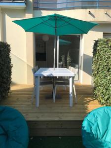 uma mesa com um guarda-chuva verde num deque em Studio Les Pétrels avec terrasse et jardinet à 2 pas de la plage em Pornichet