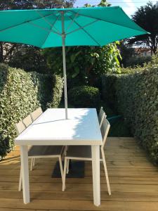 uma mesa branca com um guarda-chuva verde em cima em Studio Les Pétrels avec terrasse et jardinet à 2 pas de la plage em Pornichet