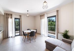 a living room with a table and chairs and windows at Melina apartments in Lefkada