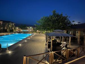 a swimming pool with an umbrella and chairs next to it at Mystras Grand Palace Resort & Spa in Mystras