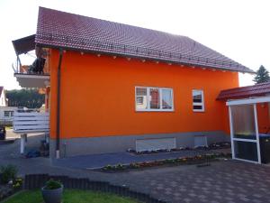 GroßkoschenにあるFerienwohnung Pfanneの白い窓と中庭のあるオレンジ色の家