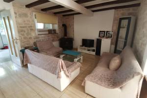 a living room with two white couches and a tv at Heritage Stone House by the Sea in Prvić Šepurine