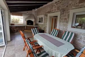 Habitación con mesa, sillas y pared de piedra. en Heritage Stone House by the Sea en Prvić Šepurine