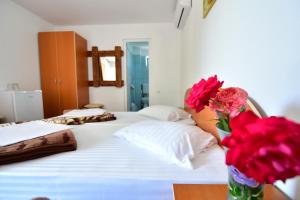 a bedroom with a bed with a vase of red roses at Vila Maya in Vama Veche