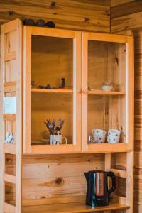 a wooden cabinet with cups and dishes in it at Kroņkalniņi in Lapmežciems