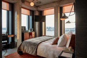 a bedroom with a large bed and large windows at Sir Adam Hotel in Amsterdam
