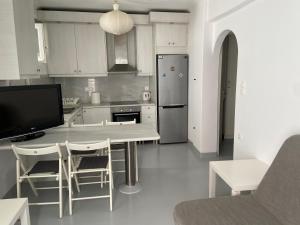 cocina con mesa y sillas y TV en Ground floor Apartment in Mykonos Town en Mykonos