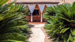 a house with palm trees in front of a patio at Casa L'Alzoni in San Teodoro