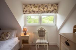 a bedroom with a bed and a chair and a window at Ghillie's Cottage in Penpont
