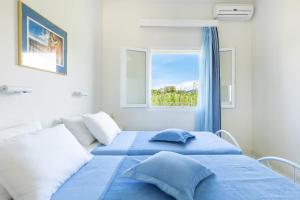 a bedroom with a blue bed and a window at Amorossa Beachfront Village by Konnect, Roda Corfu in Roda