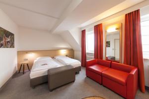 a bedroom with two beds and a red couch at Sure Hotel by Best Western Muenchen Hauptbahnhof in Munich +93 photos