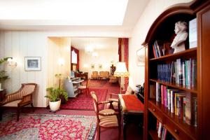 uma sala de estar com uma biblioteca com uma mesa e cadeiras em Hotel Austria - Wien em Viena