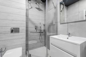 a bathroom with a shower and a sink and a toilet at VIP House Apartamenty in Sztutowo