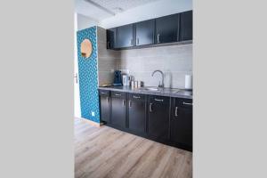 a kitchen with black cabinets and a wooden floor at CUDJOE in Dinan