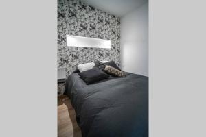a bedroom with a bed with a black comforter at CUDJOE in Dinan