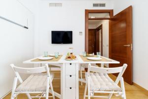 uma sala de jantar branca com uma mesa e cadeiras brancas em BHost - Studio Agua de la Victoria em Málaga
