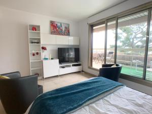a bedroom with a bed and a tv and a window at NICE, GRAND STUDIO - PISCINE - TERRASSE VUE MER in Nice
