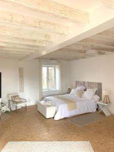 a white bedroom with a large bed and a chair at Le Domaine in La Chapelle-de-Guinchay