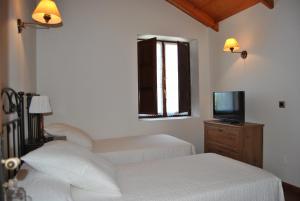 a bedroom with two beds and a tv and a window at Posada de Suesa in Suesa