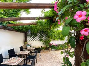 patio ze stołami, krzesłami i kwiatami w obiekcie Baglio Reale Apartments w mieście Palermo