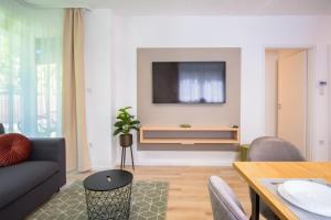 ein Wohnzimmer mit einem Sofa und einem TV an der Wand in der Unterkunft MF Batthyány Premium Residence in Siófok
