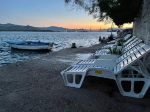 a row of white benches on the shore of a lake at Apartments Ljiljana in Klek