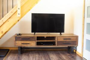 un televisor en un centro de entretenimiento de madera bajo una escalera en Red Cariboo Apartments, en Anahim Lake