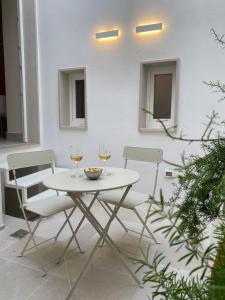 a white table with two glasses of wine at Dimore Garibaldi - Puglia Mia Apartments in Monopoli